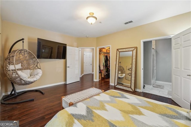 bedroom featuring a walk in closet, dark hardwood / wood-style floors, and a closet