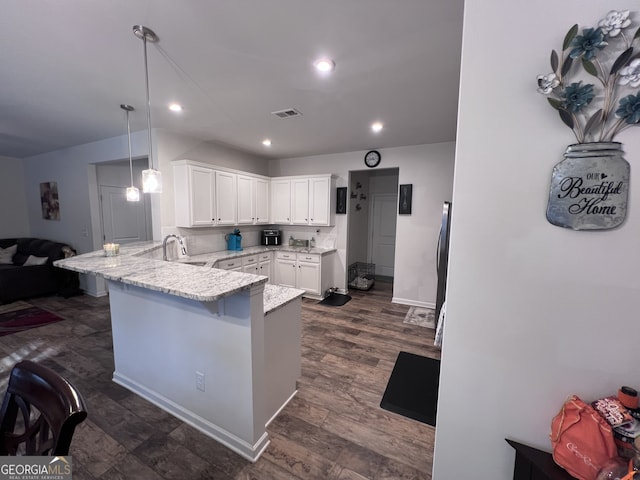 kitchen with a breakfast bar, white cabinetry, light stone counters, decorative light fixtures, and kitchen peninsula