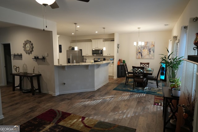 kitchen with a breakfast bar area, decorative light fixtures, kitchen peninsula, stainless steel appliances, and white cabinets