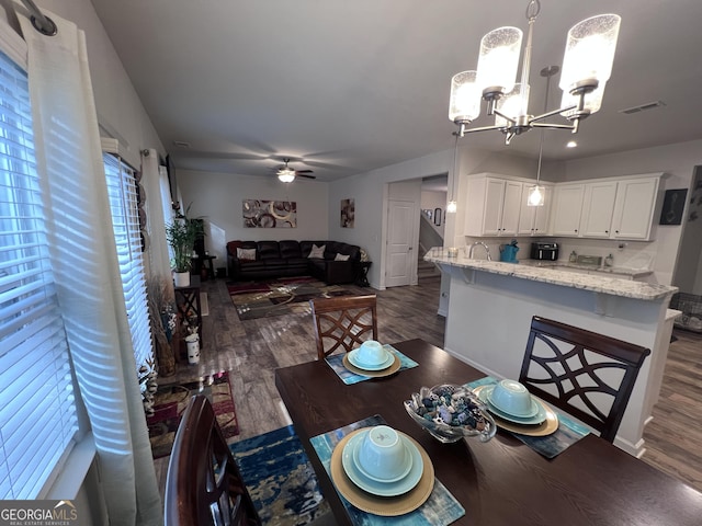 dining room with dark hardwood / wood-style flooring and ceiling fan with notable chandelier