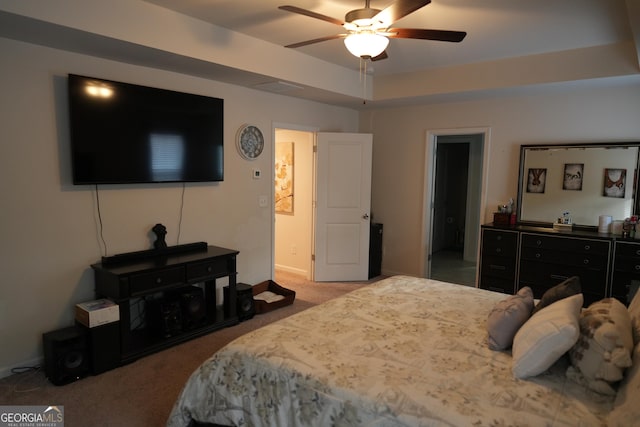 carpeted bedroom with a raised ceiling and ceiling fan