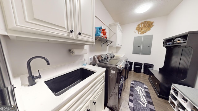 washroom featuring cabinets, electric panel, independent washer and dryer, and light wood-type flooring