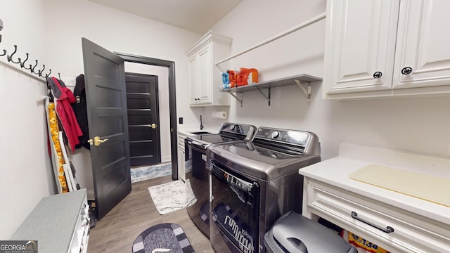 laundry area featuring hardwood / wood-style floors, washing machine and dryer, and cabinets