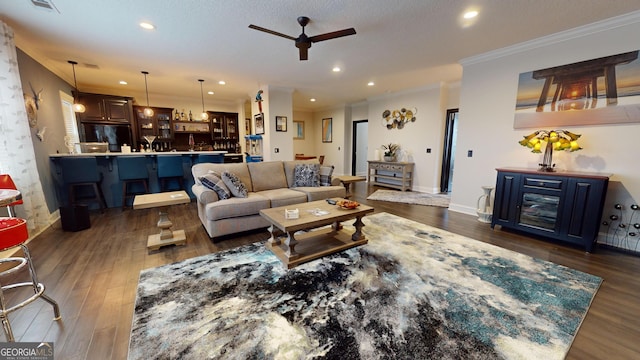 living room with dark hardwood / wood-style flooring, ornamental molding, and ceiling fan