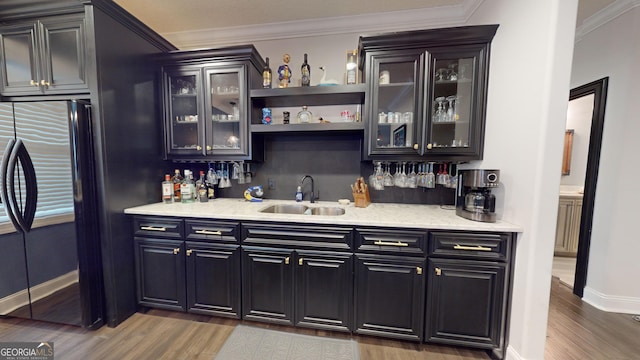 bar featuring sink, crown molding, fridge, hardwood / wood-style floors, and backsplash