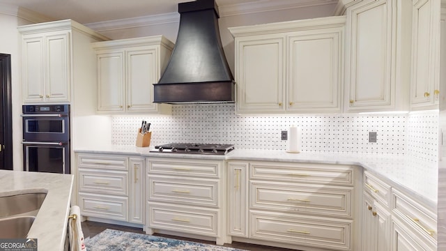 kitchen featuring stainless steel gas cooktop, custom exhaust hood, crown molding, double wall oven, and cream cabinetry