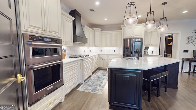 kitchen with sink, stainless steel appliances, an island with sink, a kitchen bar, and custom exhaust hood