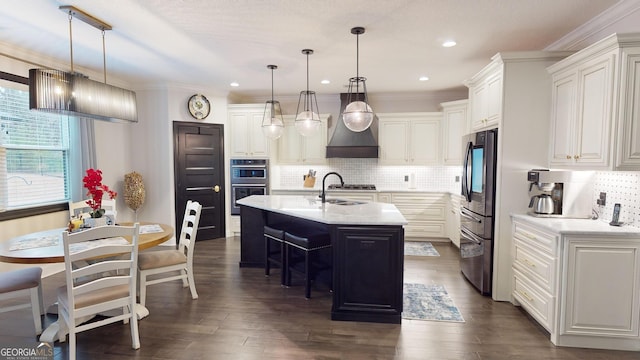 kitchen with a breakfast bar area, stainless steel fridge, white cabinets, hanging light fixtures, and a kitchen island with sink