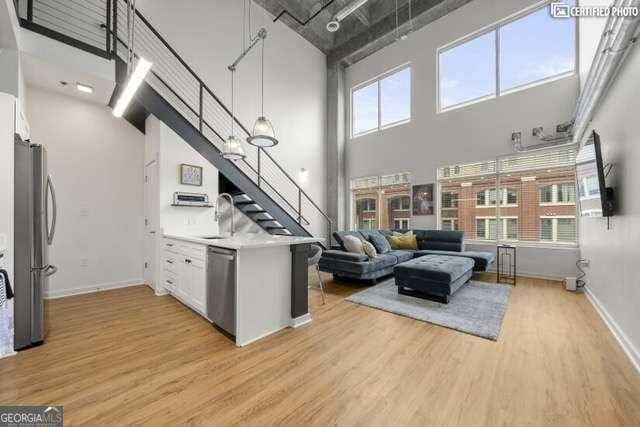 kitchen with sink, appliances with stainless steel finishes, a high ceiling, light hardwood / wood-style floors, and white cabinets