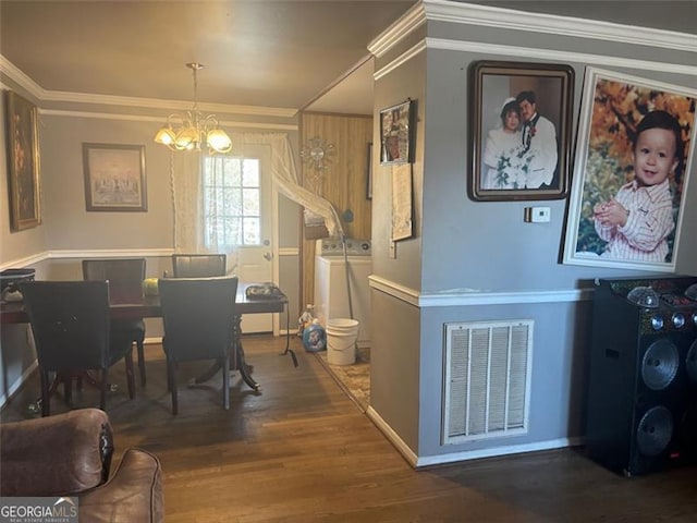 dining space with hardwood / wood-style flooring, crown molding, washer / dryer, and a notable chandelier