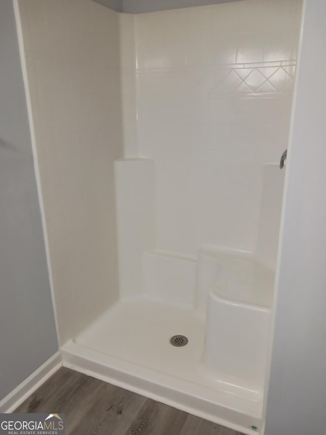 bathroom with tiled shower and hardwood / wood-style floors