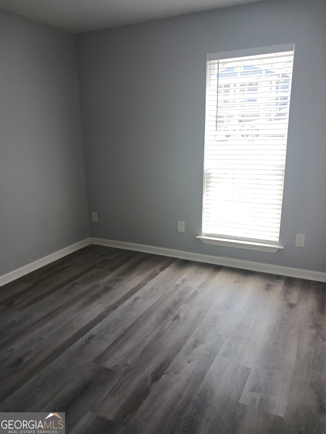 unfurnished room with dark wood-type flooring