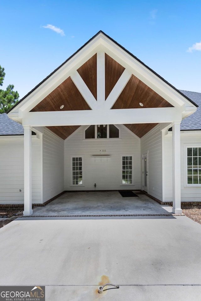 exterior space with a carport, roof with shingles, and driveway