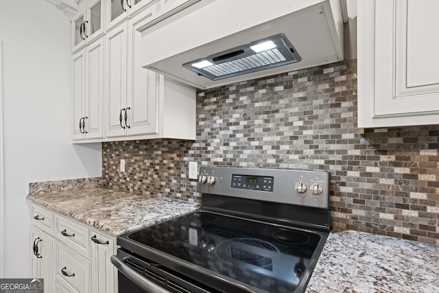 kitchen with decorative backsplash, white cabinets, stainless steel range with electric cooktop, and extractor fan