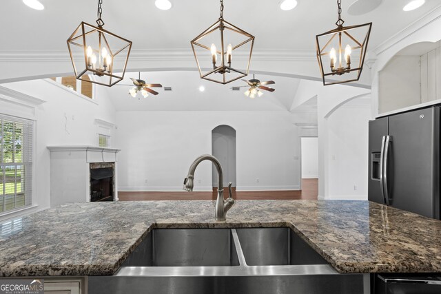 kitchen with a fireplace, stainless steel fridge with ice dispenser, ornamental molding, a sink, and open floor plan