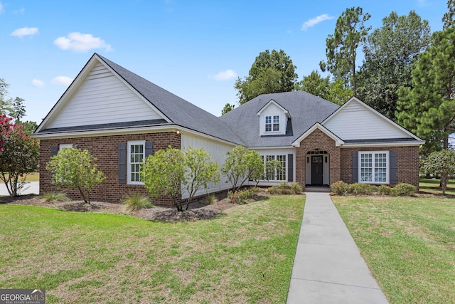 traditional-style house with brick siding, a front yard, and roof with shingles