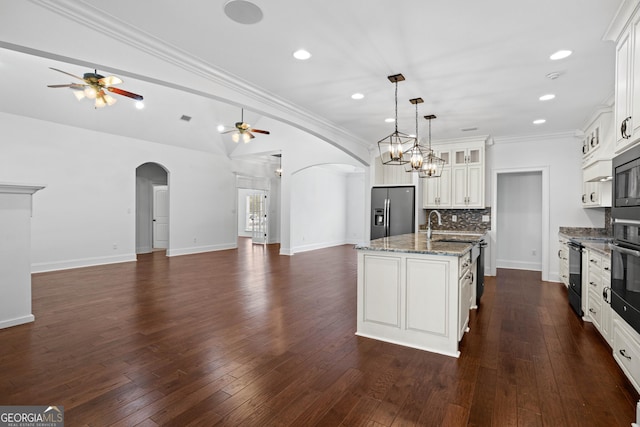 kitchen with stainless steel fridge, arched walkways, and open floor plan