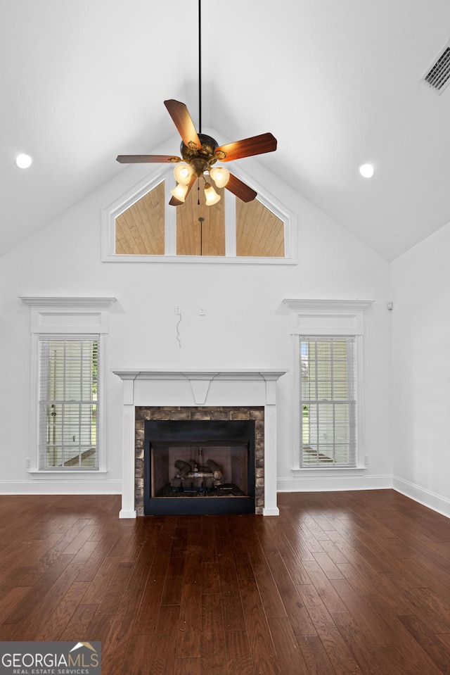 unfurnished living room with a stone fireplace, a healthy amount of sunlight, visible vents, and wood-type flooring