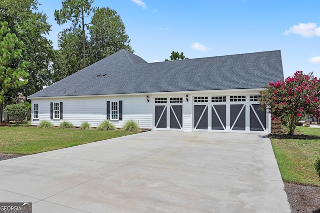 view of front of home featuring a front yard, concrete driveway, a garage, and roof with shingles