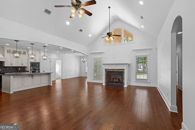 unfurnished living room featuring visible vents, arched walkways, dark wood-type flooring, and a fireplace