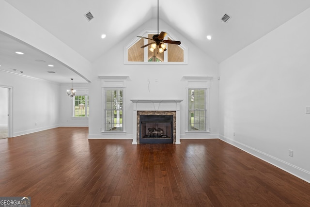 unfurnished living room with dark wood-style floors, visible vents, a stone fireplace, and high vaulted ceiling