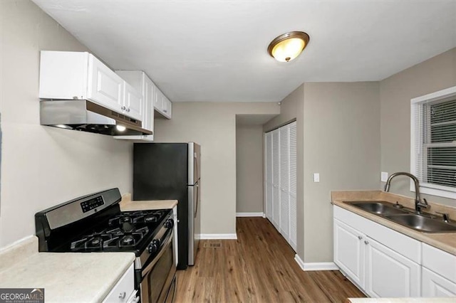 kitchen with white cabinetry, appliances with stainless steel finishes, sink, and light hardwood / wood-style flooring