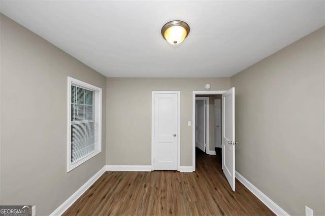 unfurnished bedroom with dark wood-type flooring