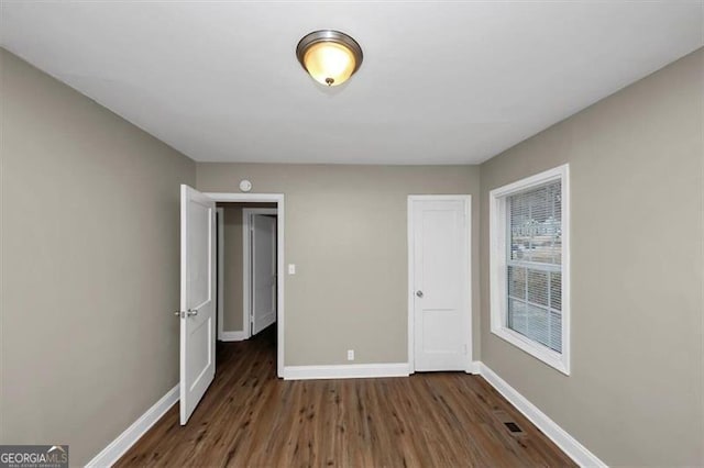 unfurnished bedroom with dark wood-type flooring