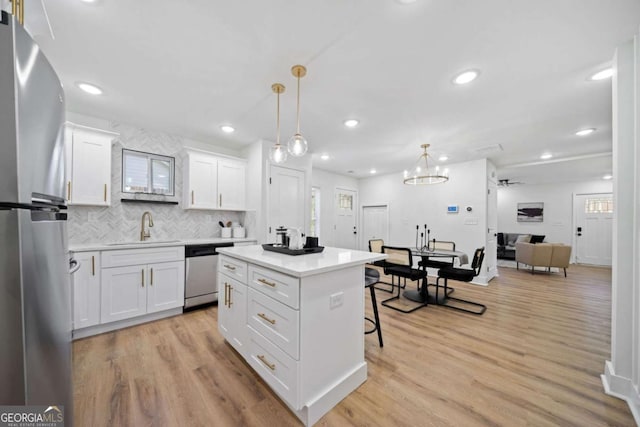 kitchen with pendant lighting, sink, white cabinets, and appliances with stainless steel finishes