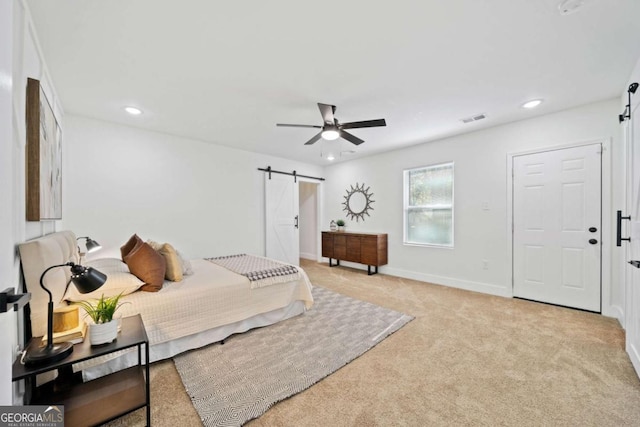 carpeted bedroom featuring ceiling fan and a barn door