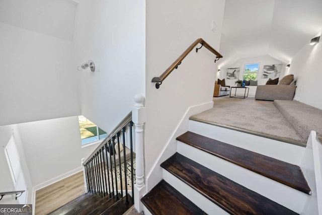 stairway featuring lofted ceiling and wood-type flooring