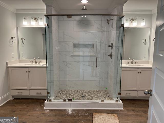 bathroom with ornamental molding, a shower with door, wood-type flooring, and vanity