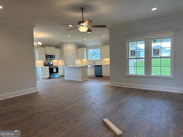 unfurnished living room with dark wood-type flooring, a healthy amount of sunlight, and ornamental molding