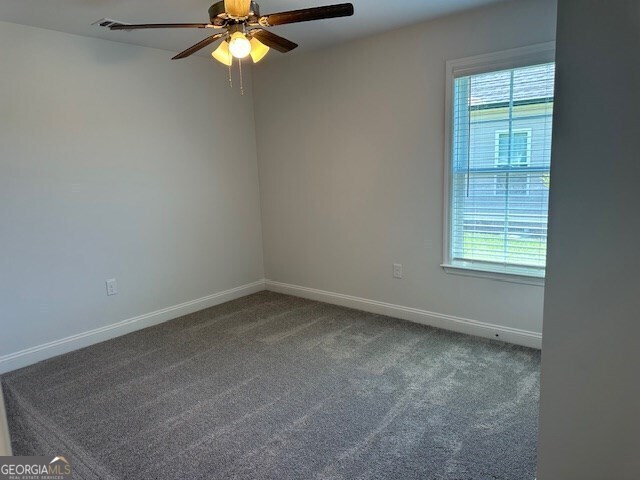 carpeted empty room featuring ceiling fan and a healthy amount of sunlight