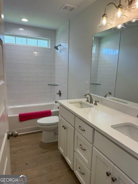 full bathroom featuring vanity, toilet, tiled shower / bath combo, and hardwood / wood-style floors