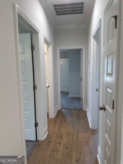 hallway with hardwood / wood-style flooring and crown molding