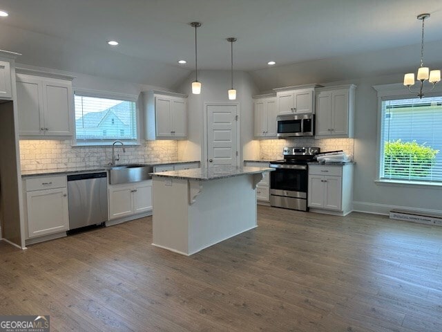 kitchen with a kitchen island, white cabinetry, appliances with stainless steel finishes, and decorative light fixtures