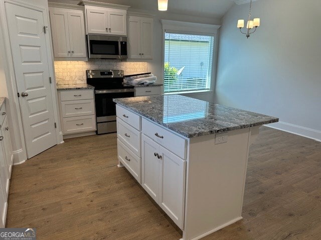 kitchen with a kitchen island, appliances with stainless steel finishes, decorative light fixtures, white cabinets, and dark wood-type flooring