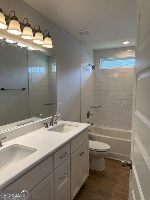 full bathroom with tiled shower / bath, hardwood / wood-style floors, vanity, and toilet