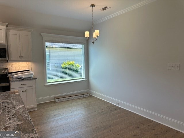 unfurnished dining area with hardwood / wood-style floors, crown molding, and a notable chandelier