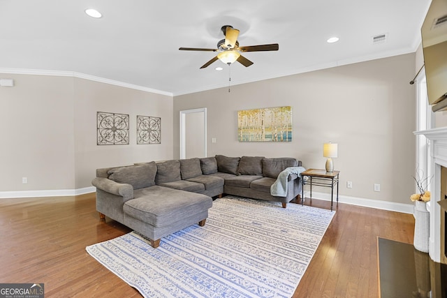 living room with baseboards, visible vents, a fireplace with flush hearth, ornamental molding, and wood finished floors