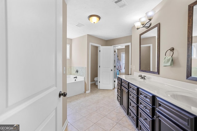 bathroom featuring tile patterned floors, toilet, vanity, a bathtub, and a healthy amount of sunlight