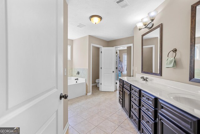 bathroom with tile patterned flooring, vanity, toilet, and a tub to relax in