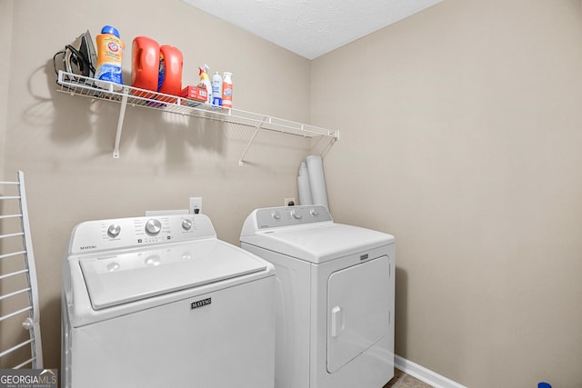 clothes washing area with separate washer and dryer and a textured ceiling