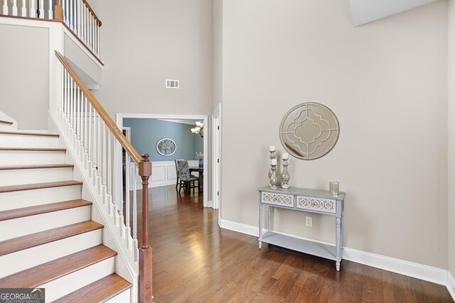 foyer with ornamental molding, a towering ceiling, and hardwood / wood-style floors