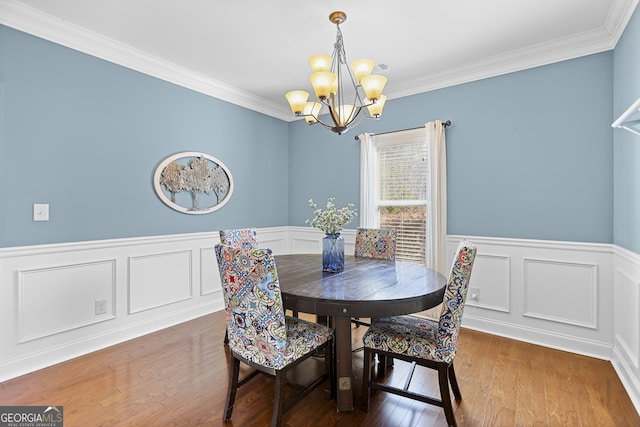 dining area with an inviting chandelier, crown molding, and wood-type flooring