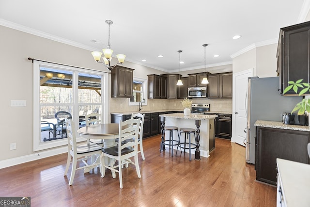 dining room featuring baseboards, dark wood-type flooring, crown molding, a notable chandelier, and recessed lighting