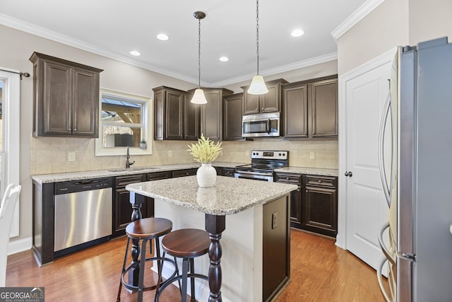 kitchen featuring a center island, appliances with stainless steel finishes, a sink, dark brown cabinets, and wood finished floors