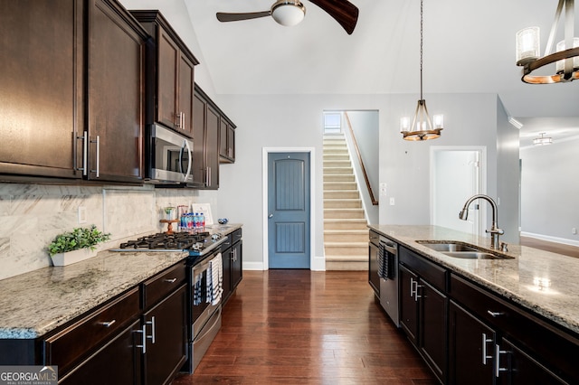 kitchen featuring appliances with stainless steel finishes, a sink, dark wood finished floors, and light stone countertops