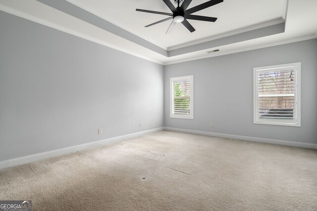 spare room with a tray ceiling, visible vents, and baseboards